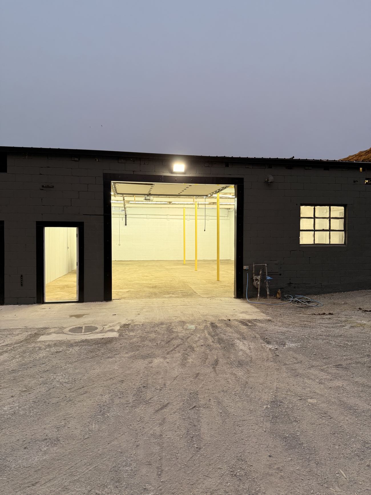 A finished unit at dusk with the overhead door open and the interior lights on.