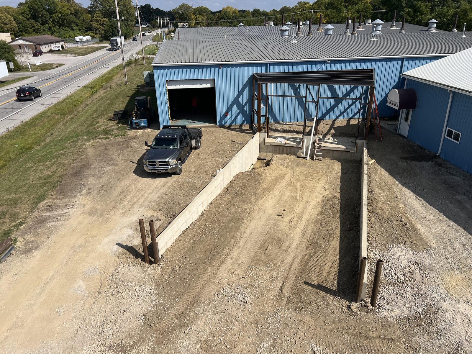 Aerial view of a new steel dock structure and poured retaining walls going in alongside an existing industrial building.
