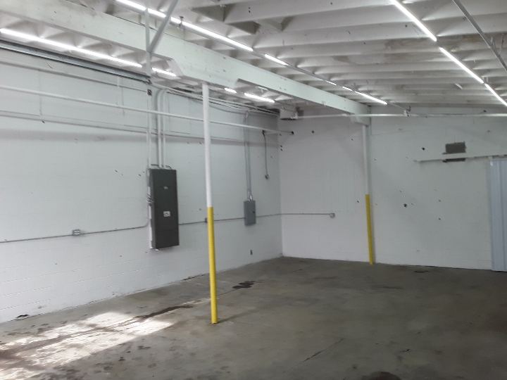 Zone D after renovation: the same bay, white walls and liner panel, LED strip lighting and safety-yellow posts.
