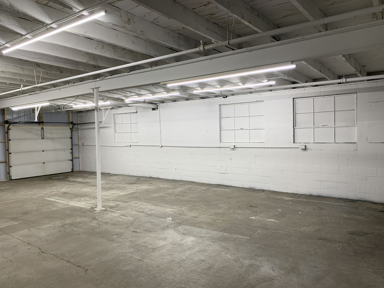 Zone E after renovation: the same bay, white walls and liner panel, LED lighting, clean floor.