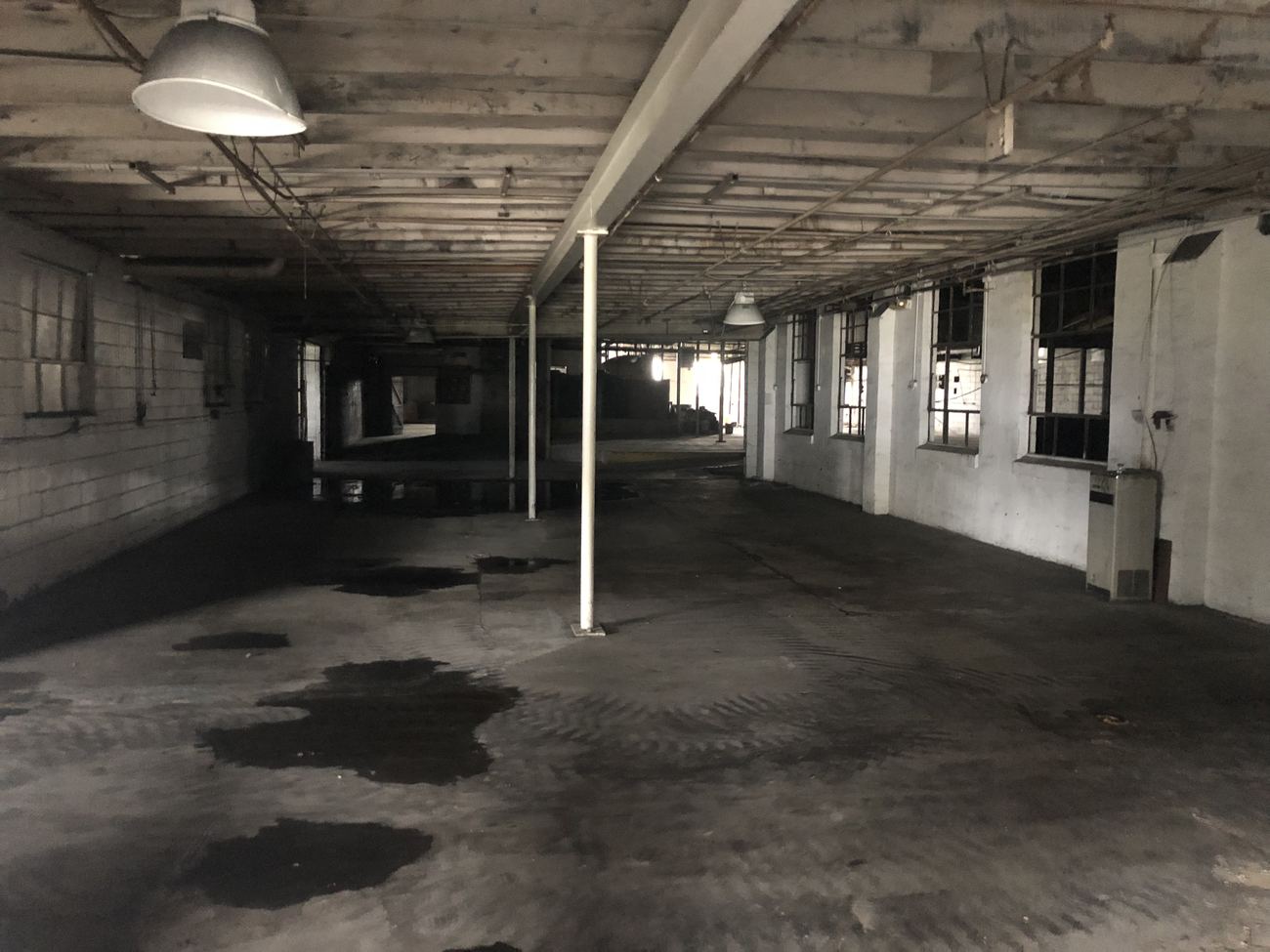 Zone E before renovation: a long dark bay with a stained floor and a row of grimy windows.