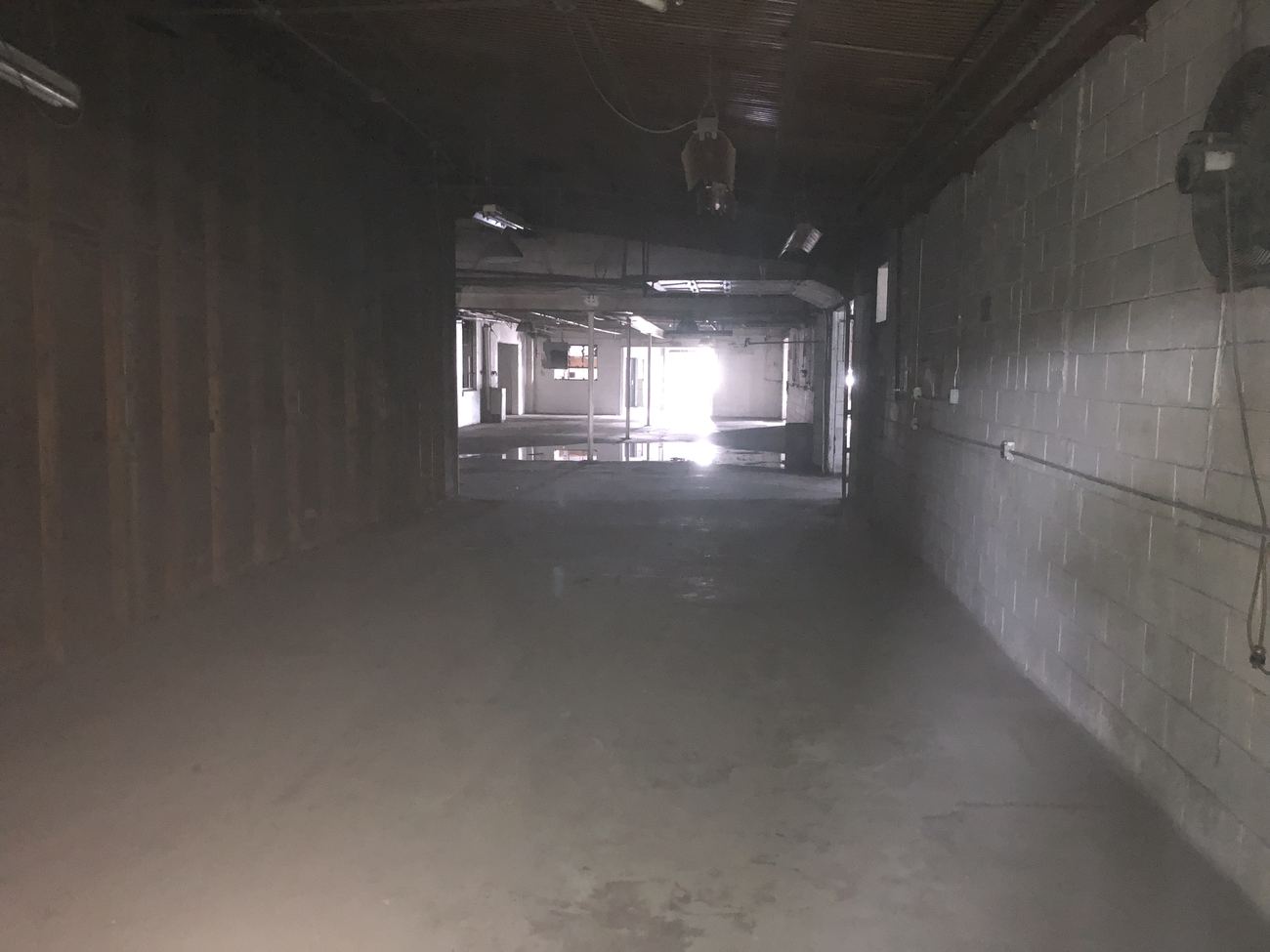 Zone R before renovation: a long unlit corridor of a bay, walls unfinished.