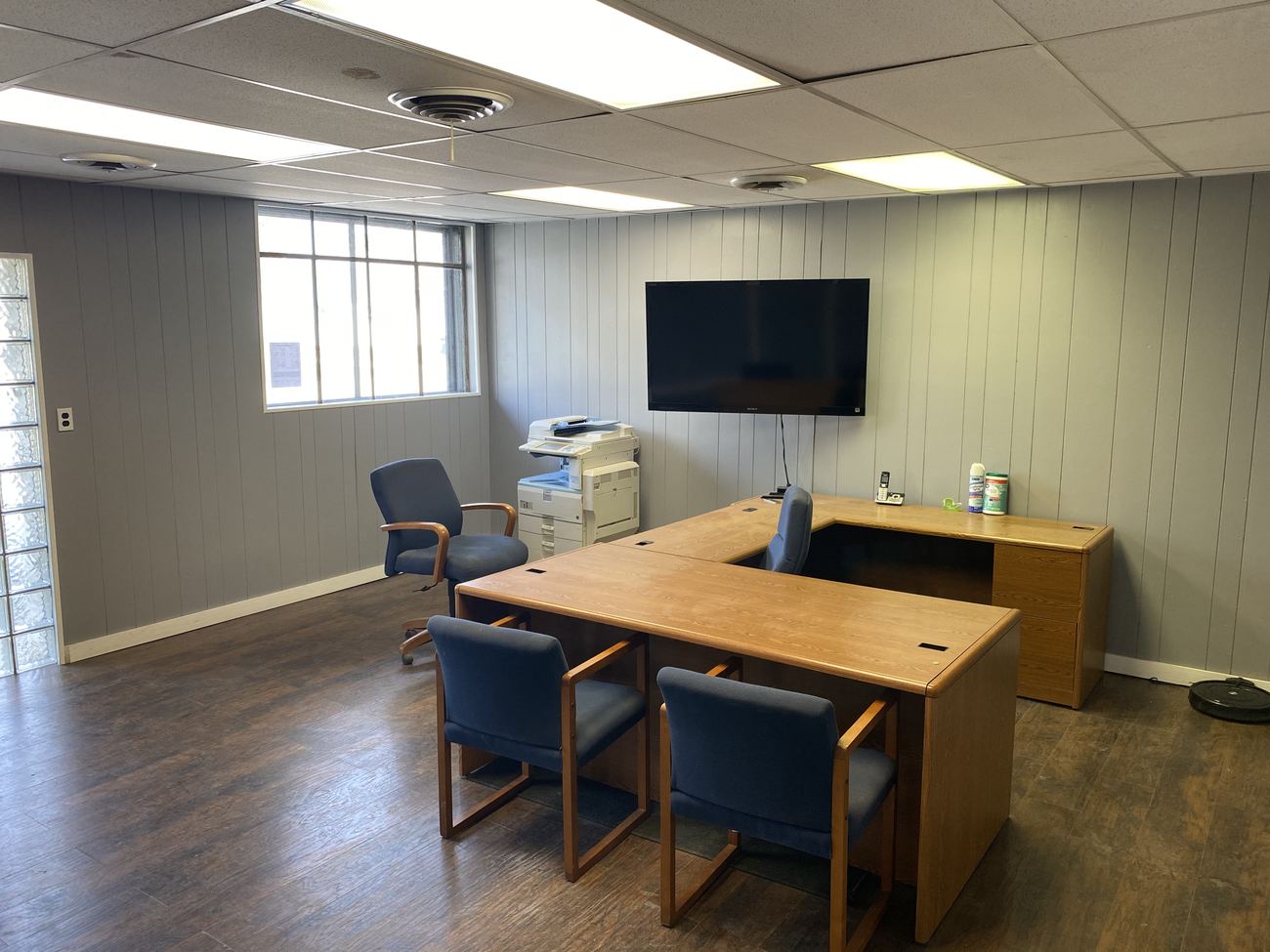 Zone T office after renovation: finished panelled walls, drop ceiling, wood floor and a tenant working in it.